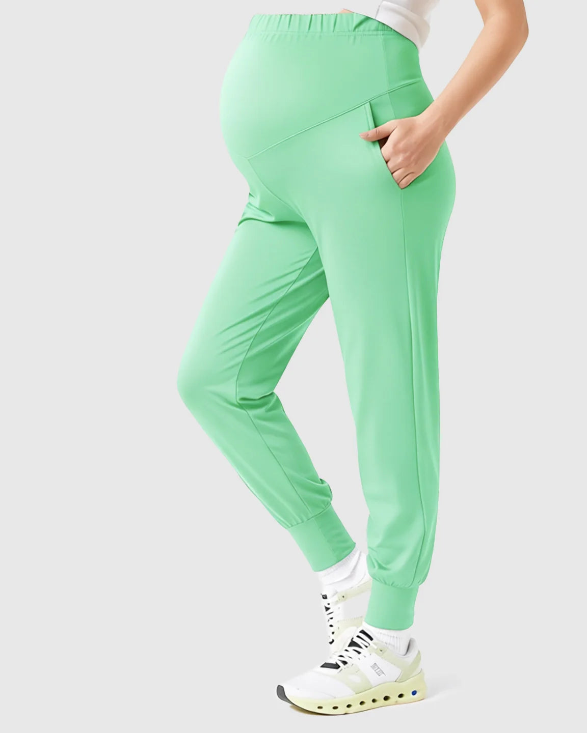 Mint green supportive slim-fitting maternity joggers with a high-waist design and side pockets.